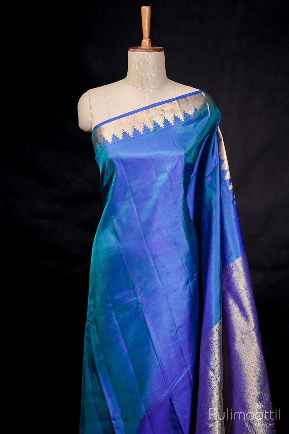 Peacock blue Kanchipuram soft silk saree with plain body and golden temple border draped on mannequin.