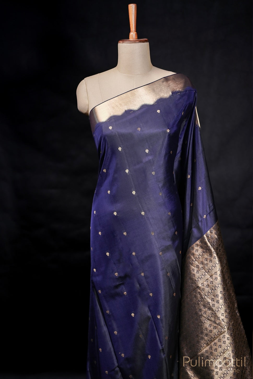 Dark blue Kanchipuram soft silk saree with golden buttas and gold border draped on mannequin.