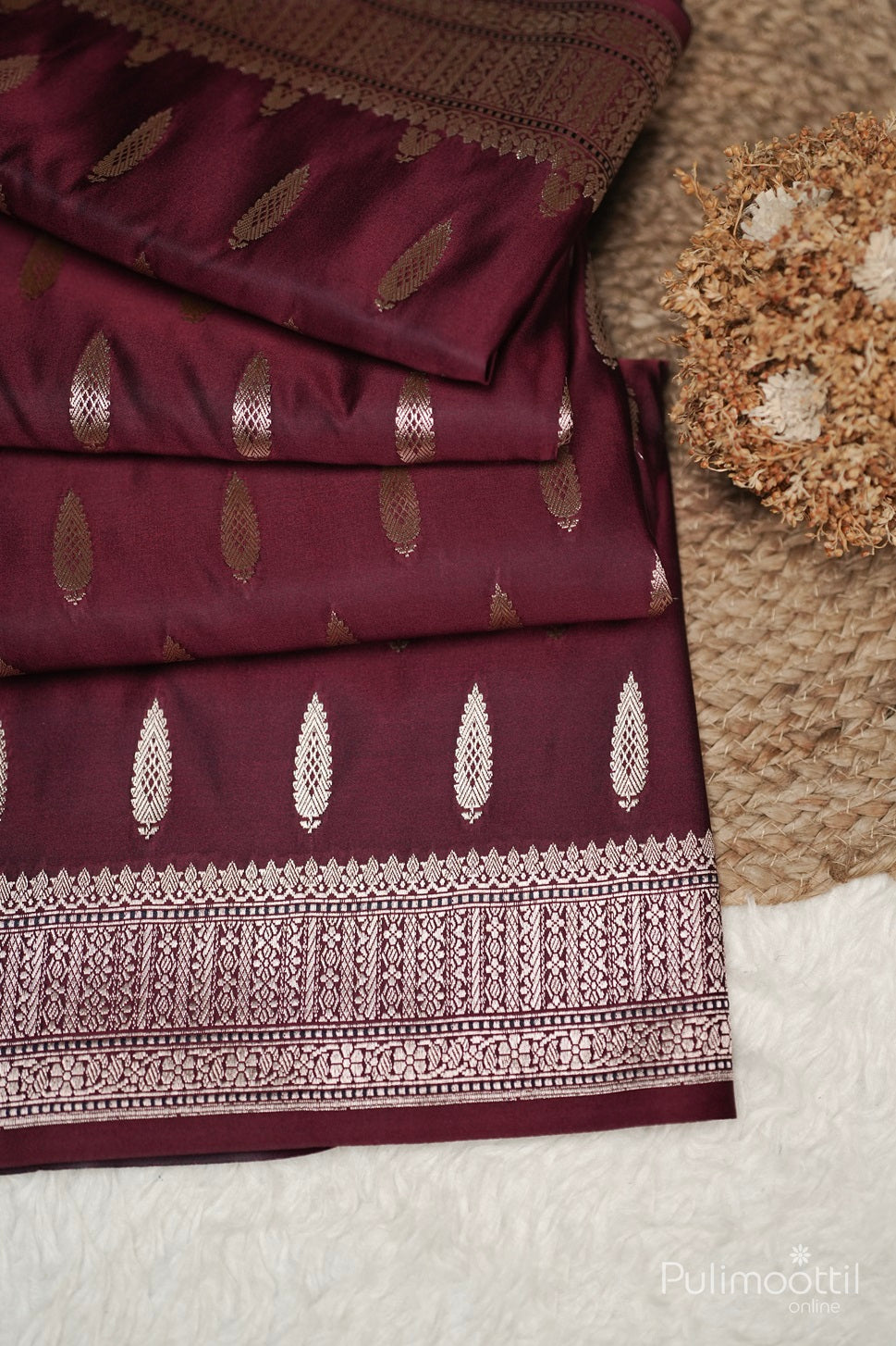 Close-up of golden zari buttas and intricate designer border on maroon Mashru silk Banarasi saree, ideal for bridal saree and party wear from Pulimoottil Silks Thrissur.