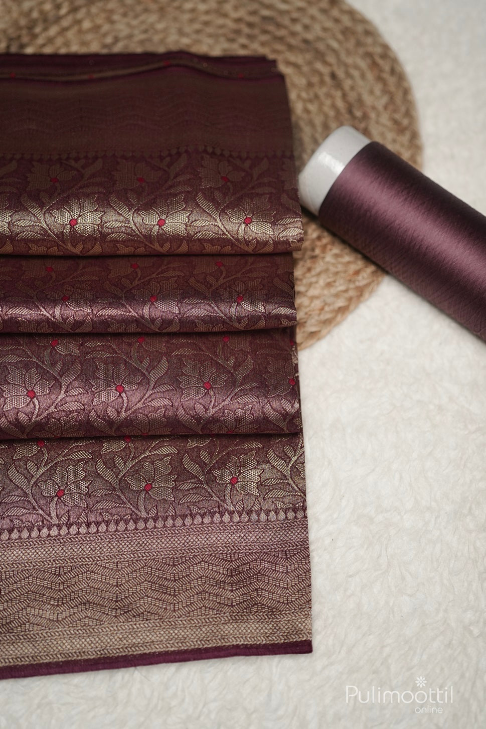 Close-up of Saree Pallu with heavy gold zari weave, deep maroon tassels, and floral body pattern with red accents.