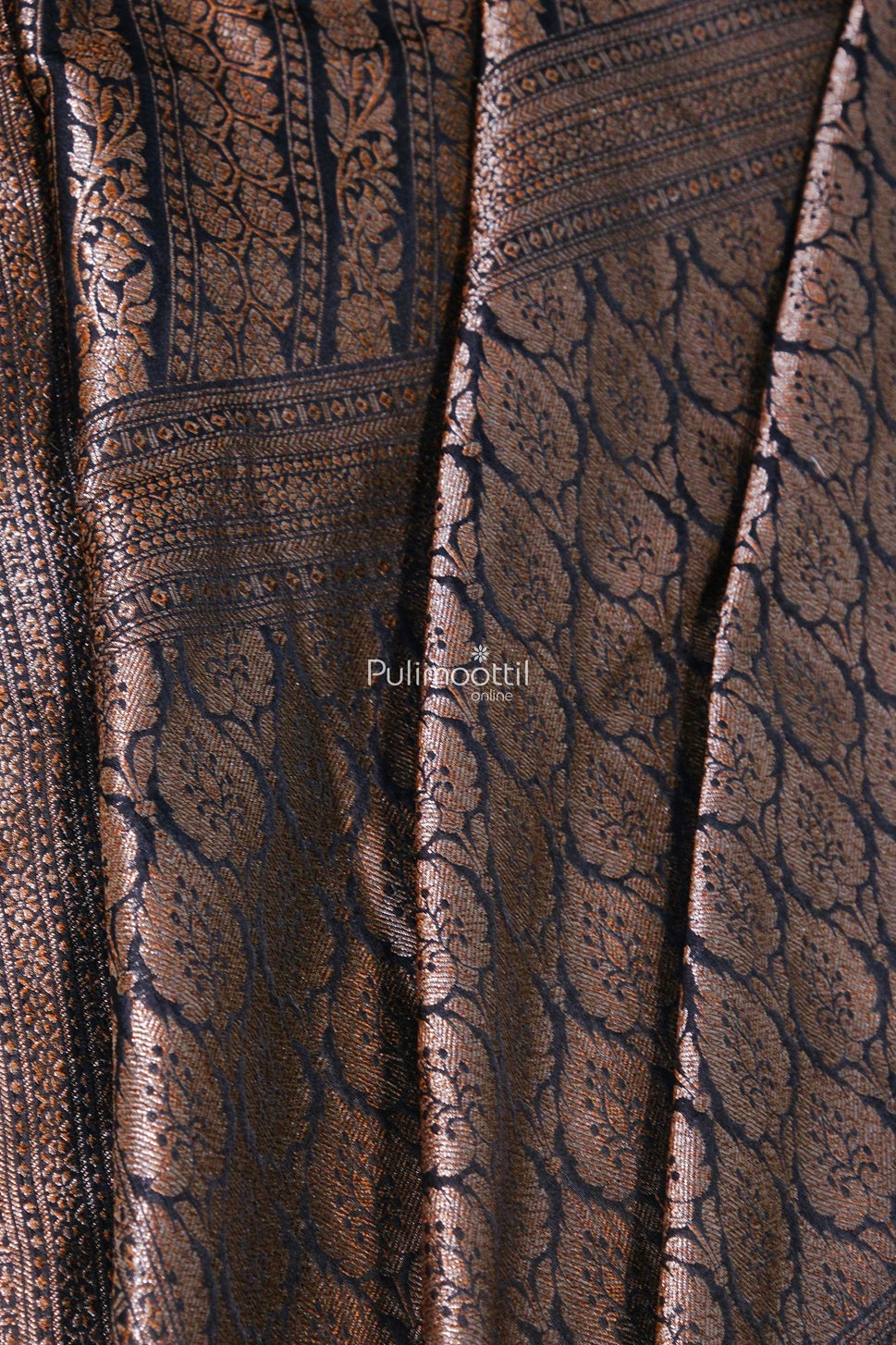 Detailed close-up of the saree showcasing its intricate floral motifs and textured weave in shimmering copper thread over a dark black base.