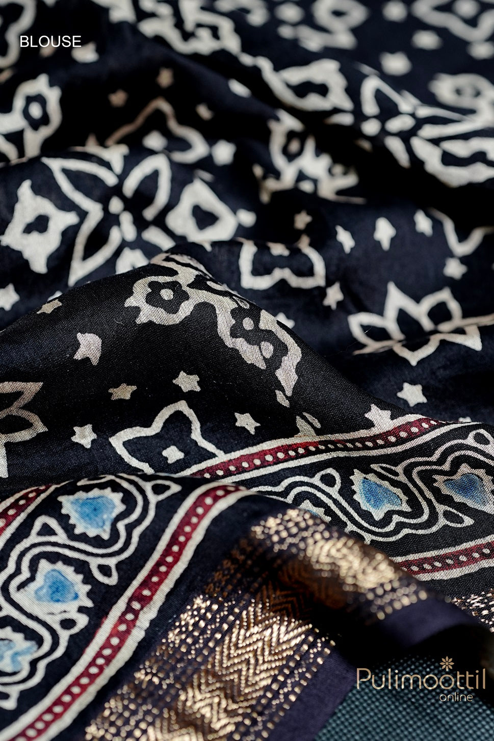 Close-up of Black Colour Chandheri Silk Saree blouse fabric featuring floral print and detailed zari border with rich patterns.