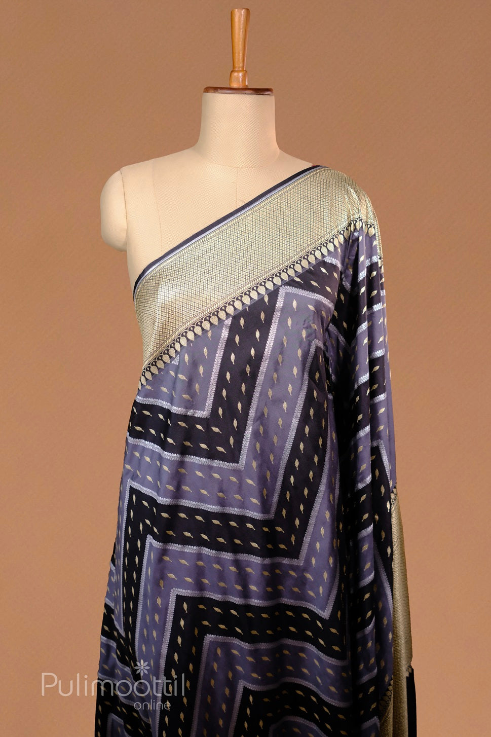 Mannequin draped in a navy-blue and lavender geometric-patterned silk saree, featuring gold accents and a gold-checked border.