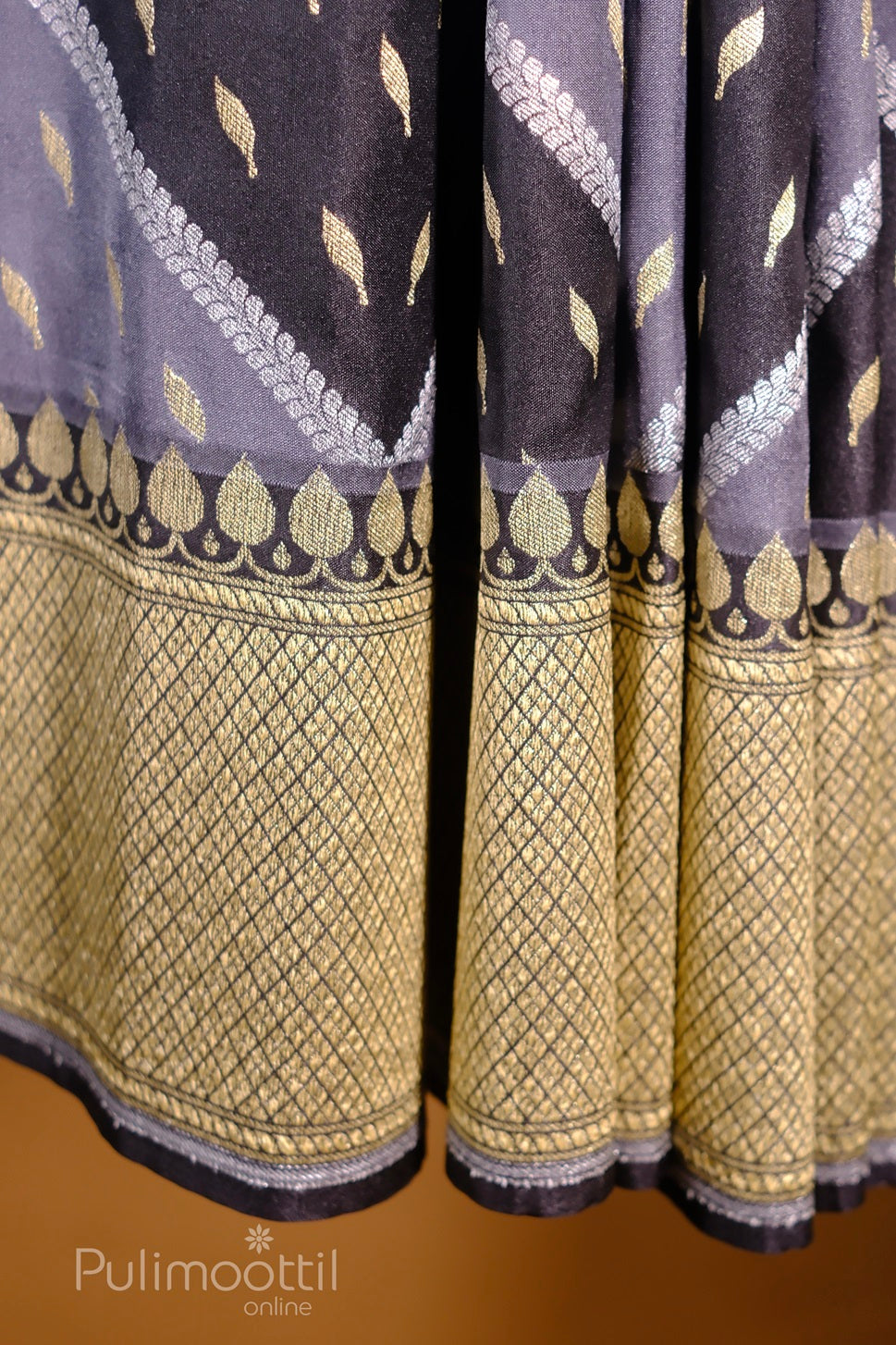 Draped navy-blue silk saree with lavender chevron pattern, gold butta motifs, and gold-checked zari border.