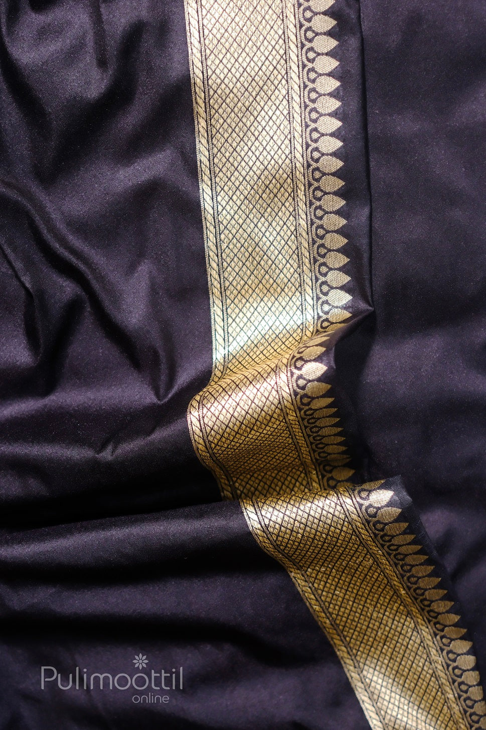 Navy‑blue silk saree close‑up showing gold‑checked zari border with teardrop motifs.