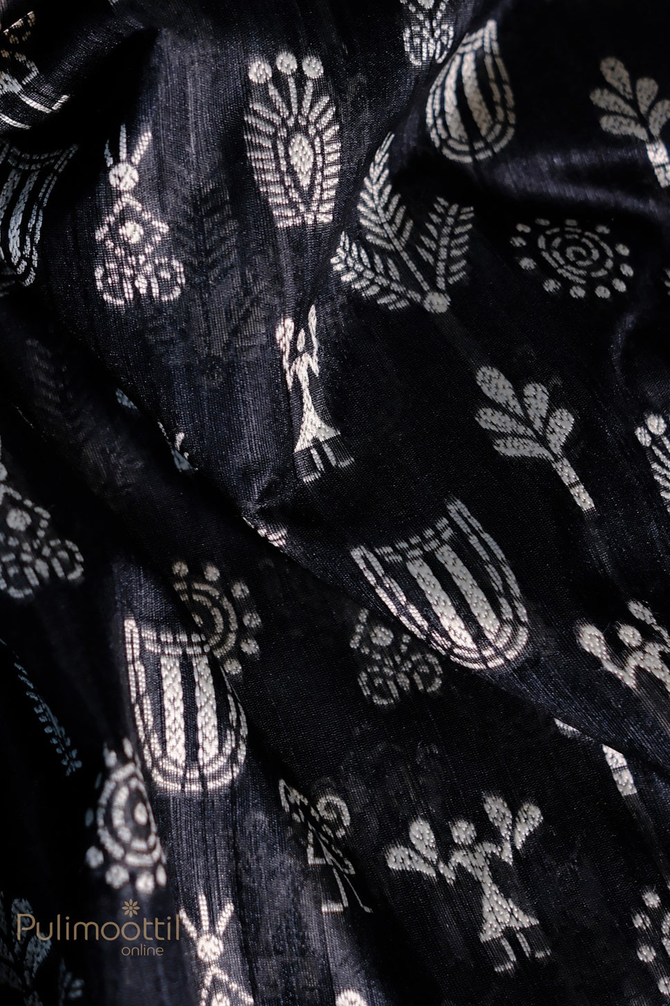 Detailed close-up of the black saree with silver tribal motifs, including floral and geometric patterns, showcasing the artistry and craftsmanship of the fabric.