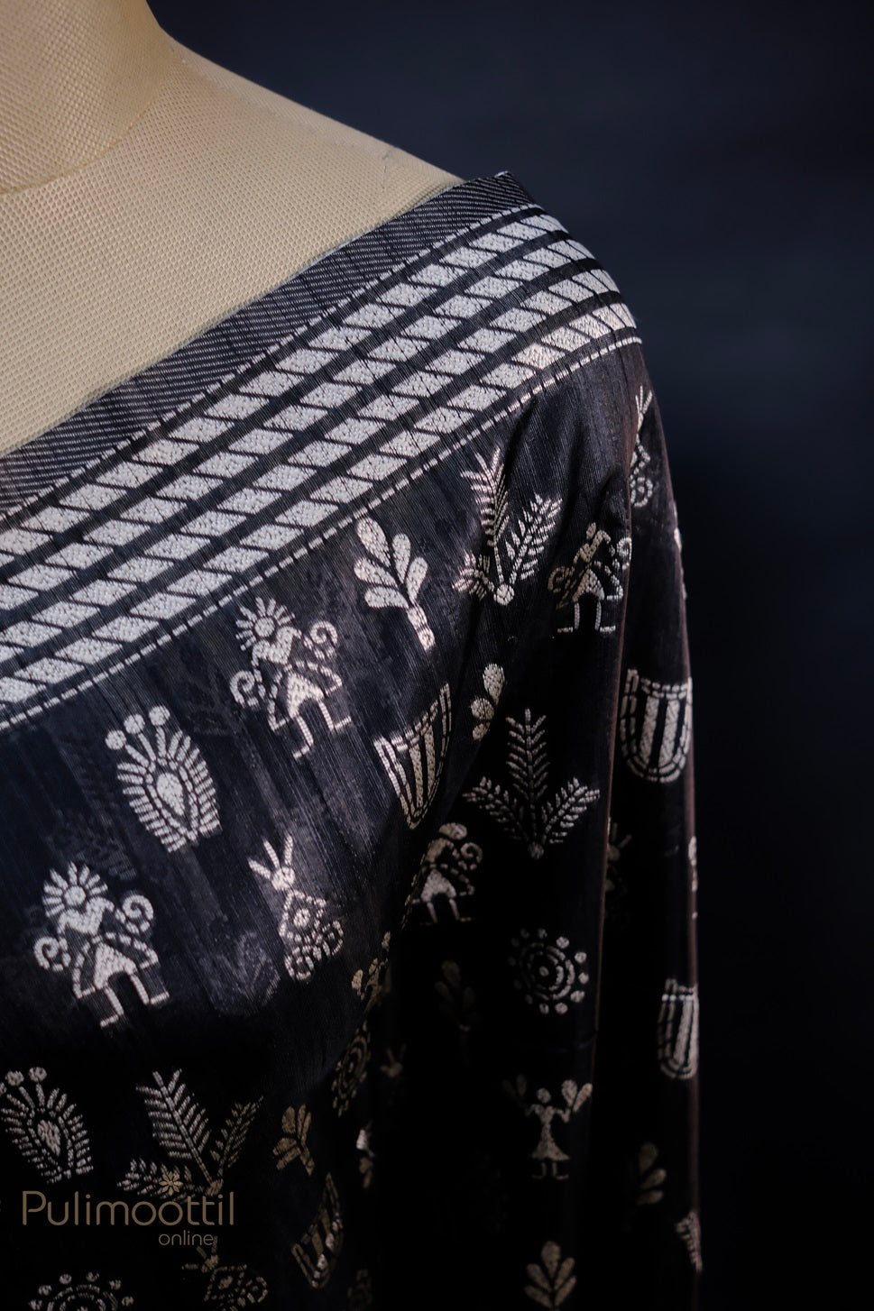Close-up shot of the black saree showing the beautiful silver tribal motifs and striped silver border, emphasizing the detailed ethnic design elements.
