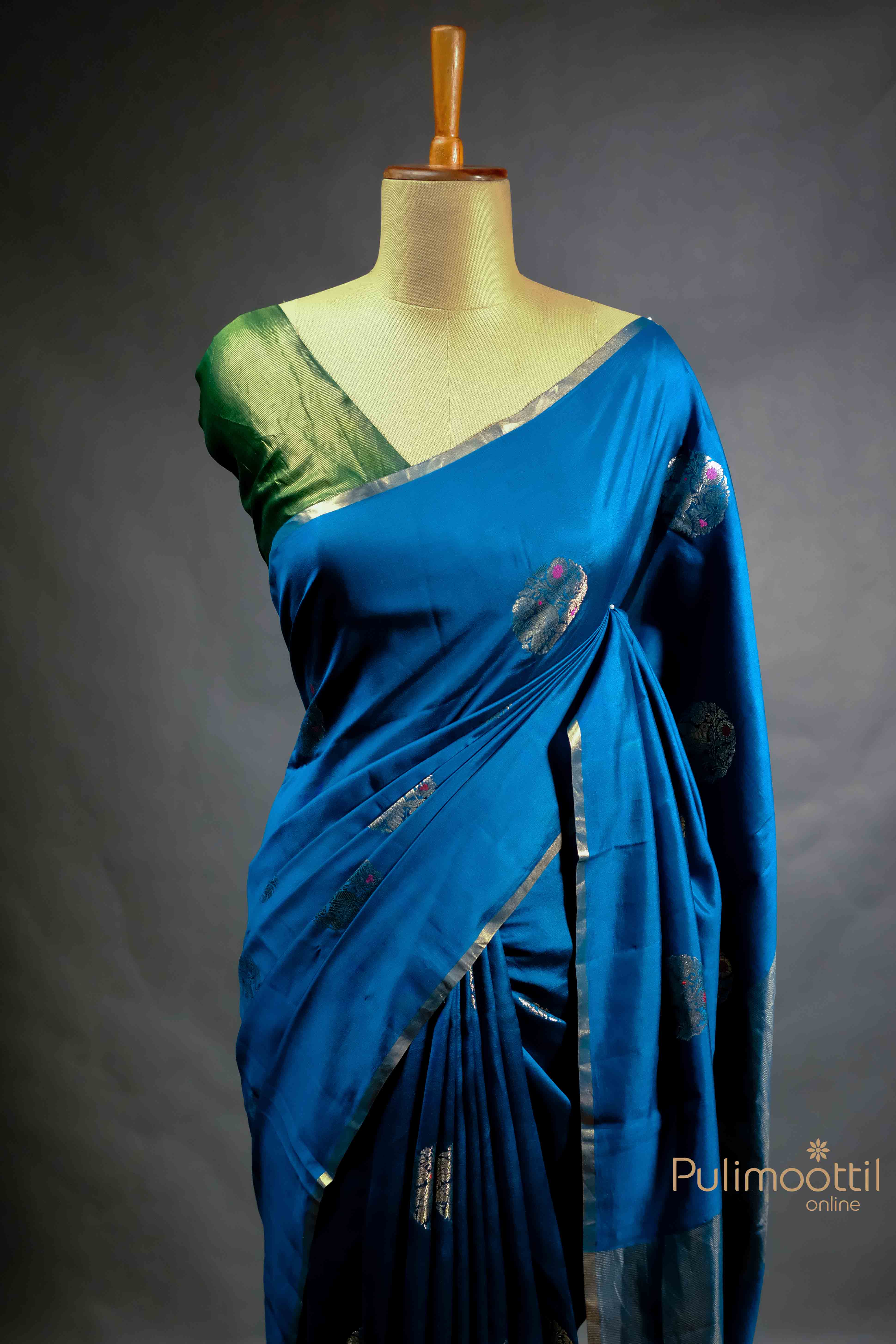 Blue Chiniya Silk Saree with light golden motifs and floral body design, draped elegantly on a mannequin.