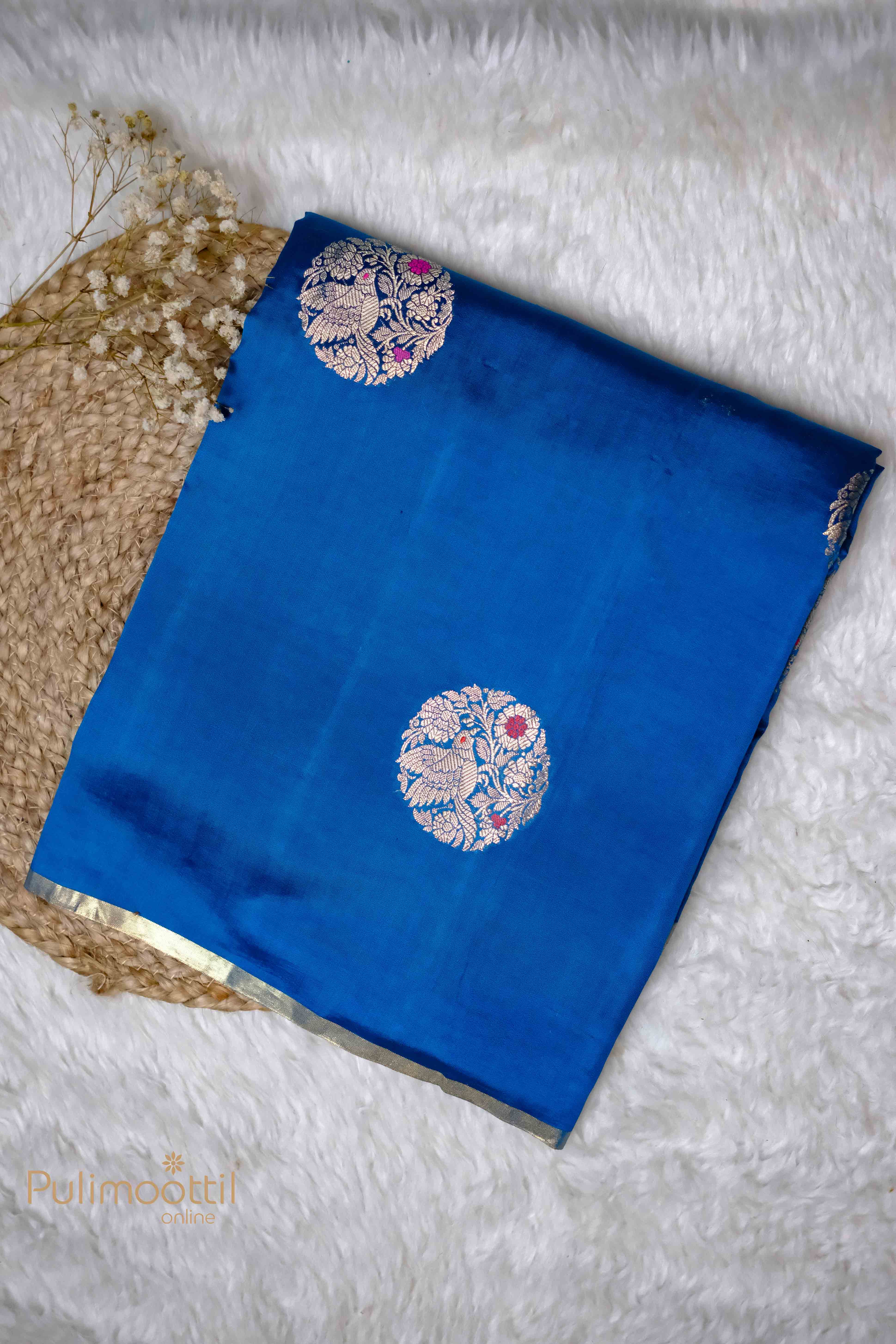 Blue Chiniya Silk Saree with golden floral motifs, neatly folded for display.