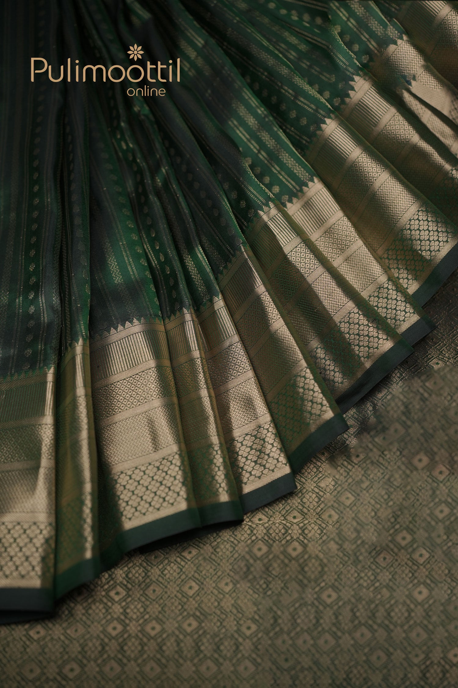 alt="Bottle‑green Kanchipuram silk saree pleats with golden zari border and small butta motifs, Pulimoottil Online branding"