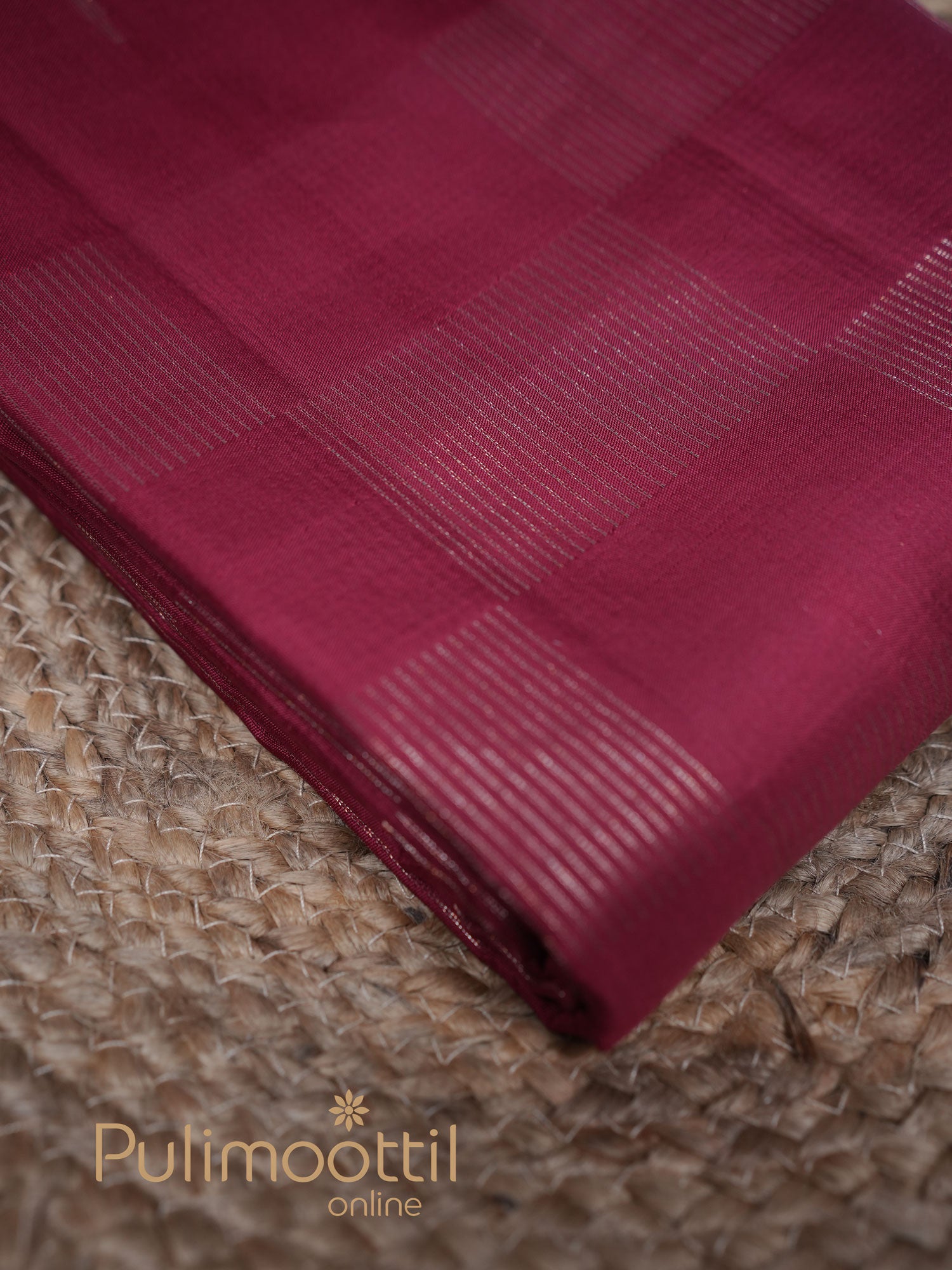 Maroon Kanchipuram cotton silk saree with subtle checked zari pattern, neatly folded on a woven mat background – ideal for traditional and festive occasions.