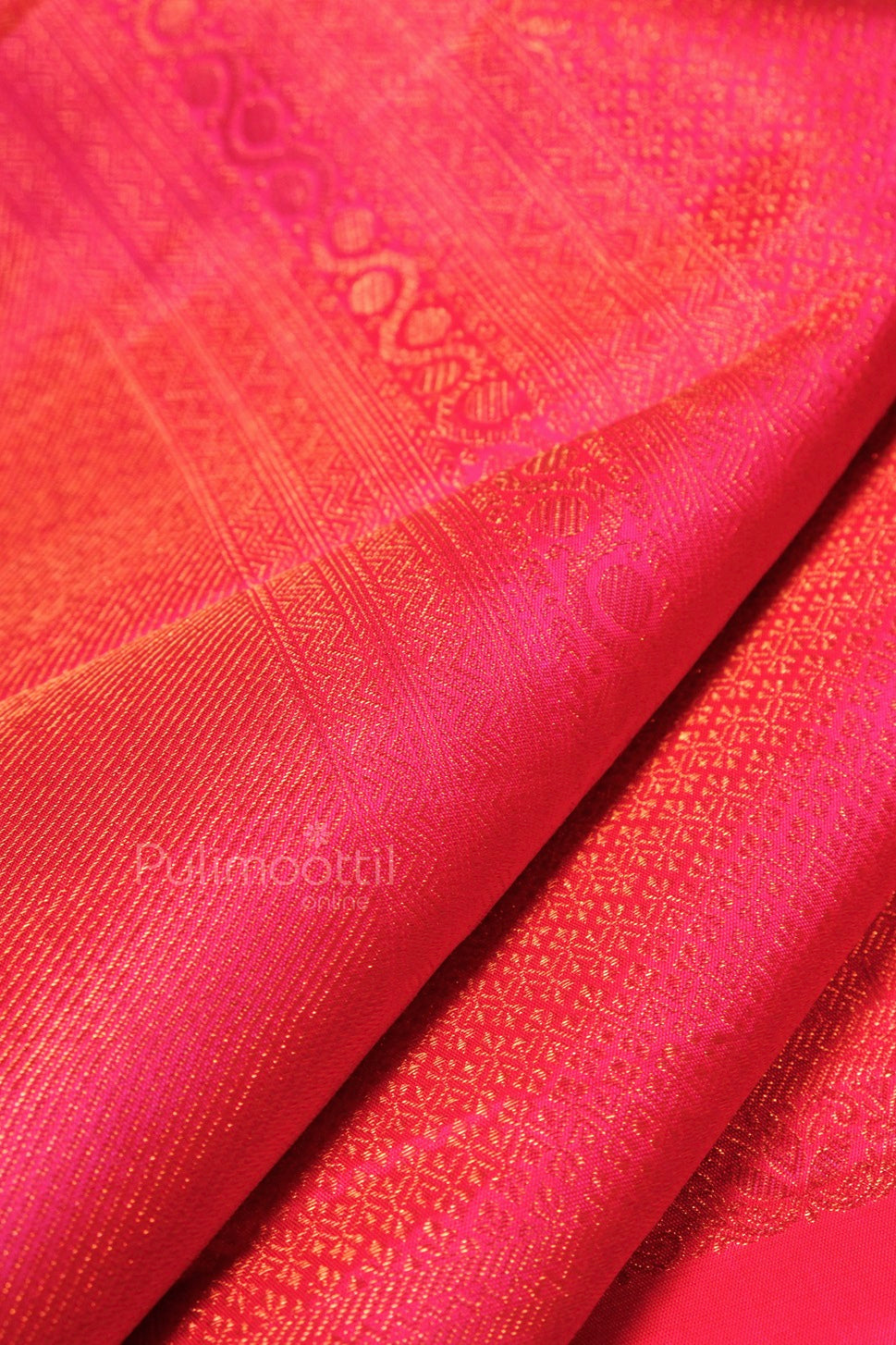 Draped section of plum Kanchipuram bridal saree highlighting intricate gold zari geometric motifs and sheen