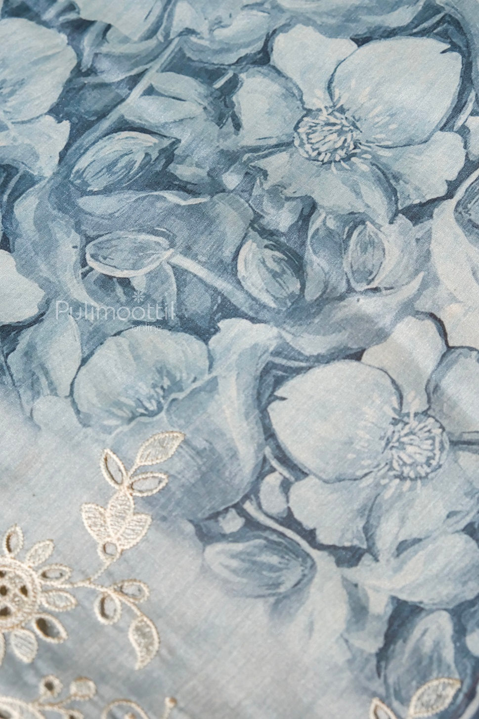 "Close-up of watercolor-style blue floral print on fabric with delicate thread embroidery for ethnic or festive wear