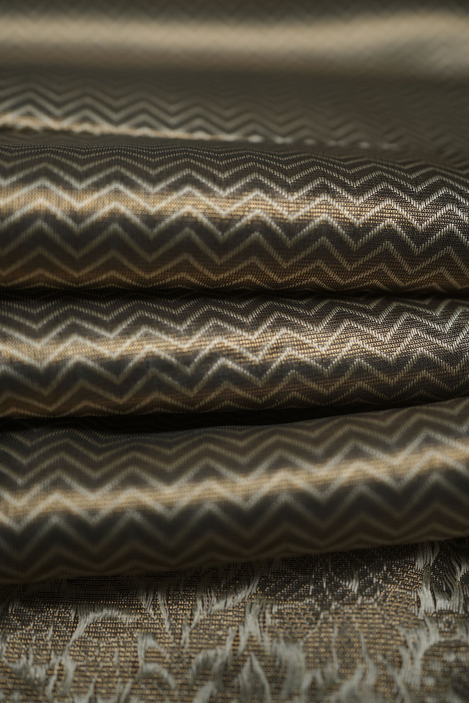 Gold-toned semi-silk jacquard fabric with zigzag chevron weave, soft folds highlighting its sheen.