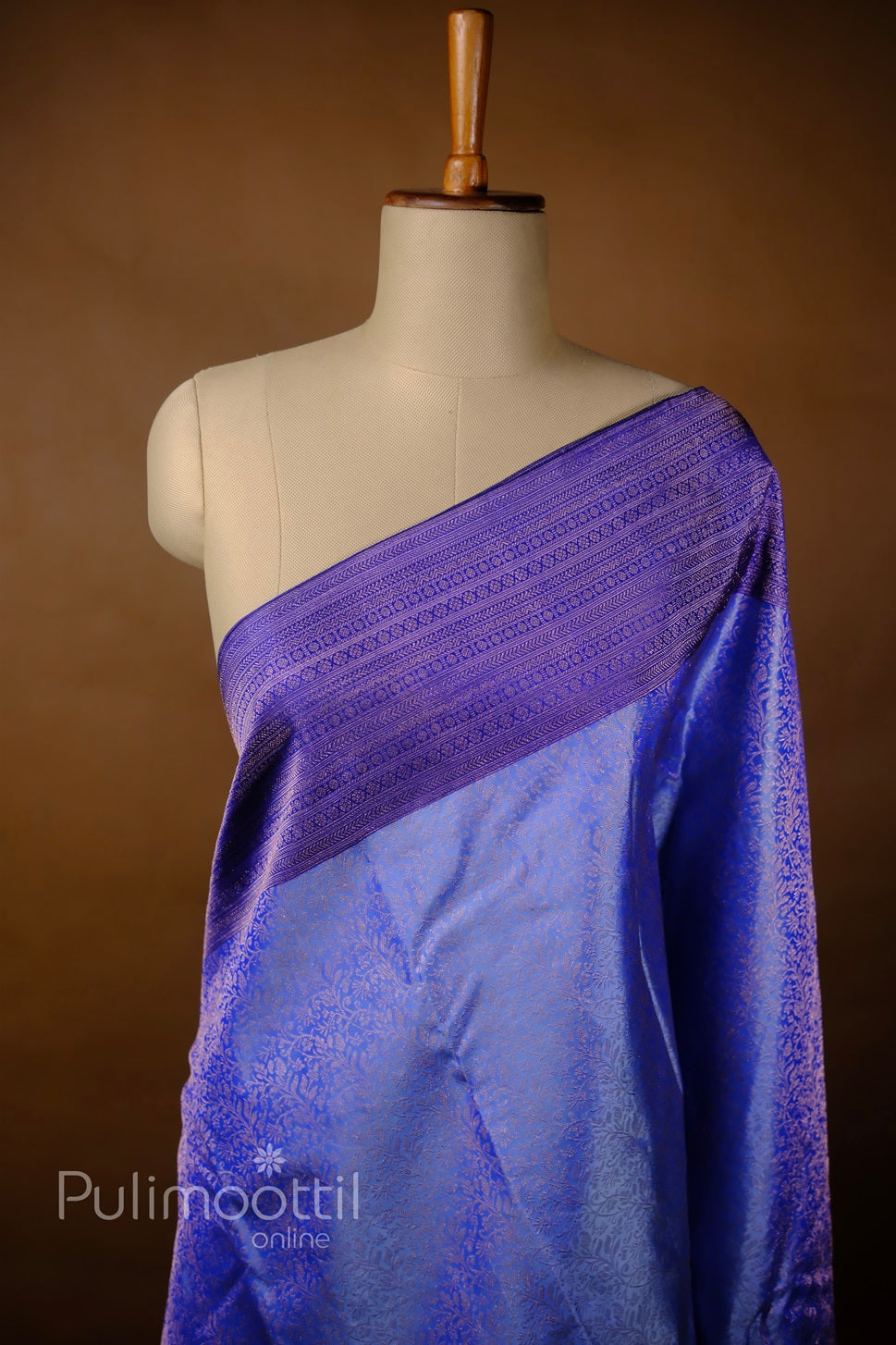 Draped purple Kanchipuram silk wedding saree on mannequin, showcasing gold geometric zari brocade border.