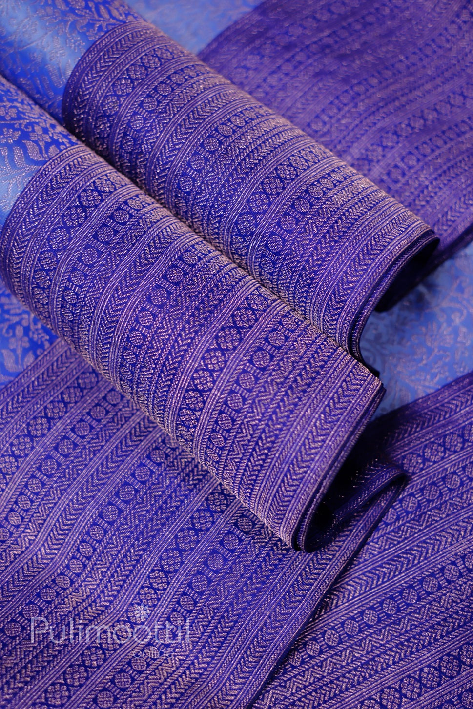 Draped royal purple Kanchipuram silk saree with intricate gold-zari micro-motif weave and lustrous sheen.