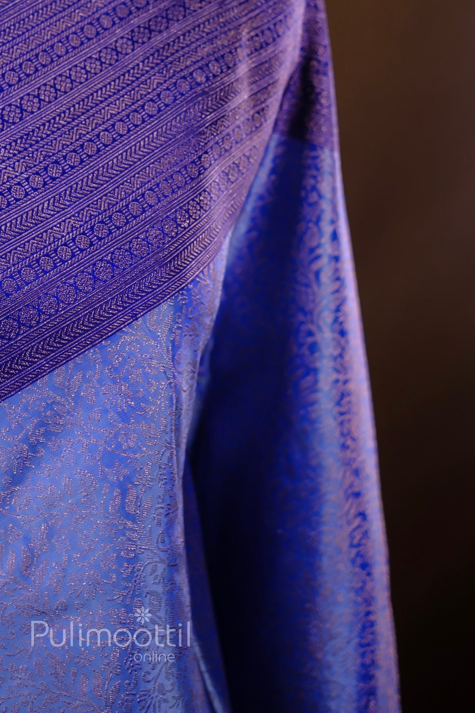 Draped royal purple-blue Kanchipuram silk saree showing delicate gold-zari weave and luxurious sheen.