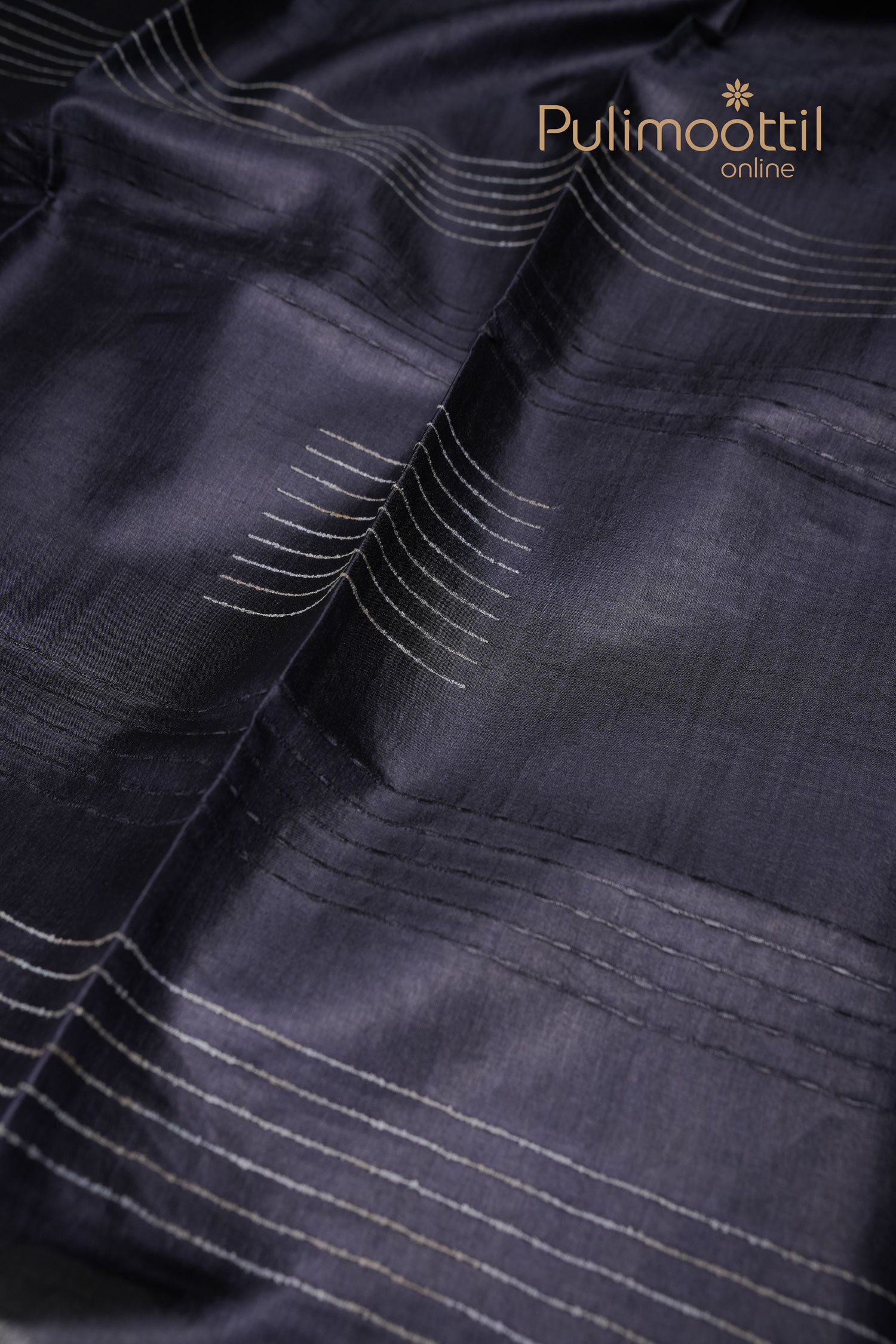 Charcoal black Tussar silk saree featuring subtle self-thread striped patterns across the body, without a border – Pulimoottil branding at the top right