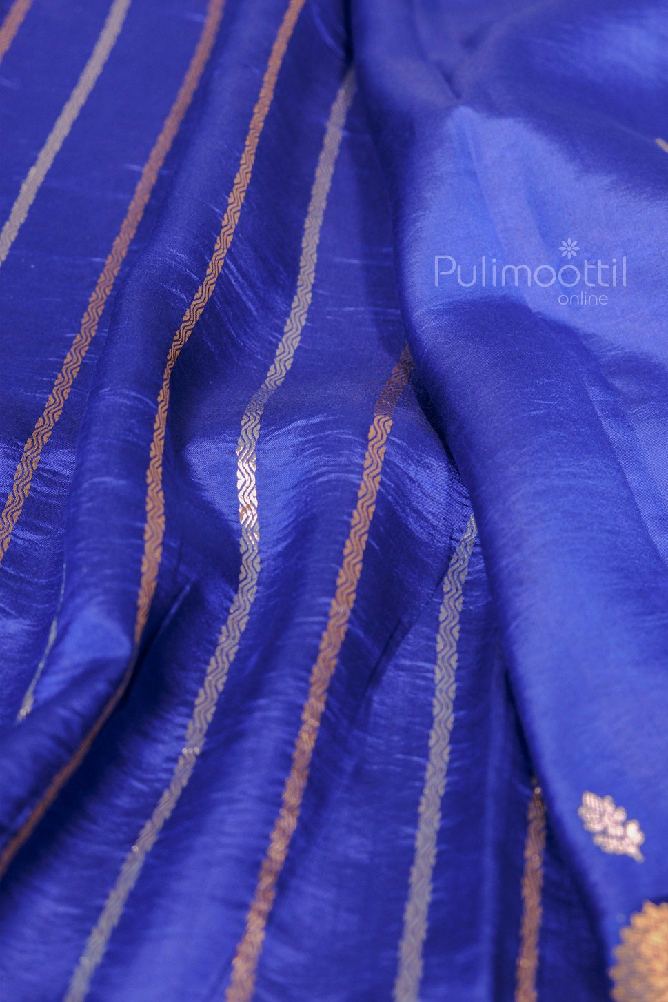 Pallu of blue silk saree with golden striped zari work and soft pleats, giving a luxurious finish.