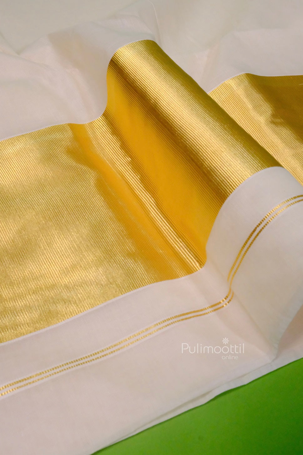 Close-up of a cream Kerala saree with shiny gold zari border, neatly folded on a light background