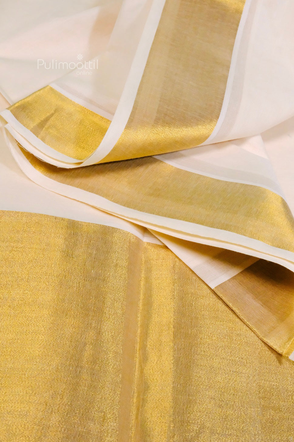 Cream Kerala saree with shimmering gold zari border, elegantly folded with peach flowers on a burlap backdrop