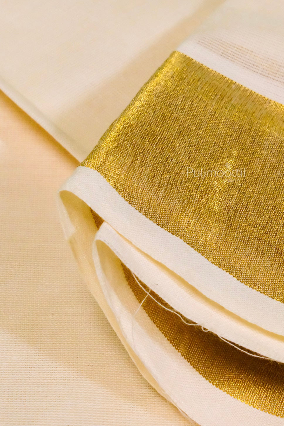 "Traditional cream Kerala saree with detailed gold zari border, neatly folded with white and yellow flowers on a textured burlap background