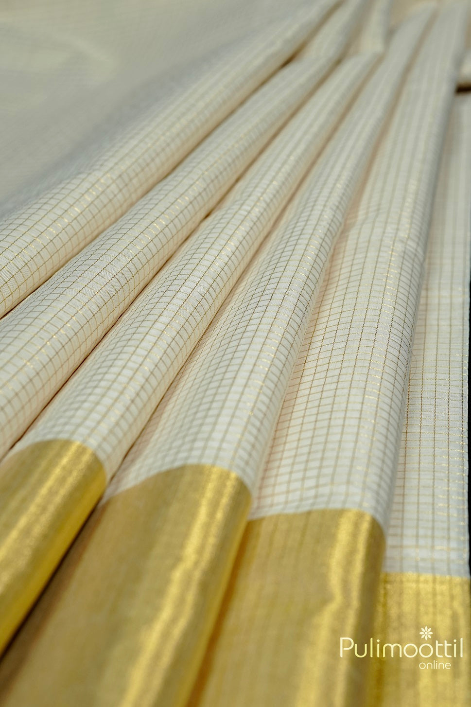 Close-up of Cream Colour Kerala Traditional Handloom Saree featuring golden zari check design and a golden tissue border, elegantly folded.