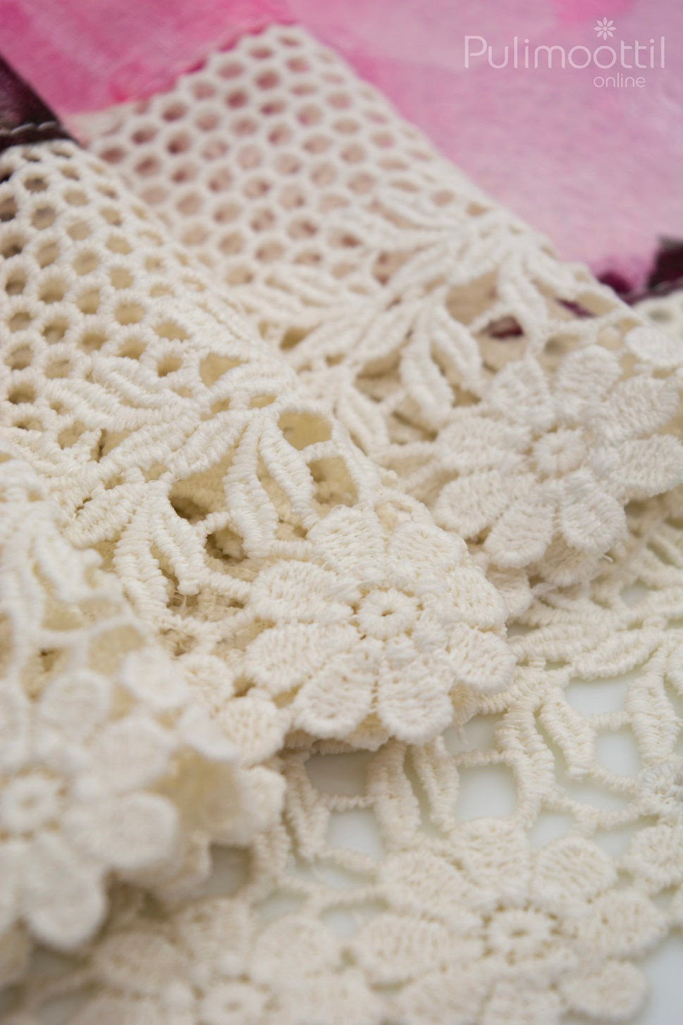 Close-up of delicate cream Crosia lace border with floral embroidery on linen saree, highlighting fine handcrafted texture against a soft floral print backdrop.