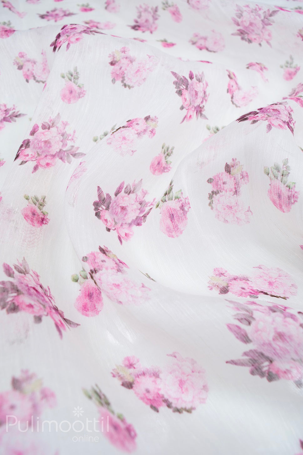 Close-up of cream linen saree fabric featuring all-over multicolour floral print in soft pink tones, highlighting the lightweight and breathable texture.