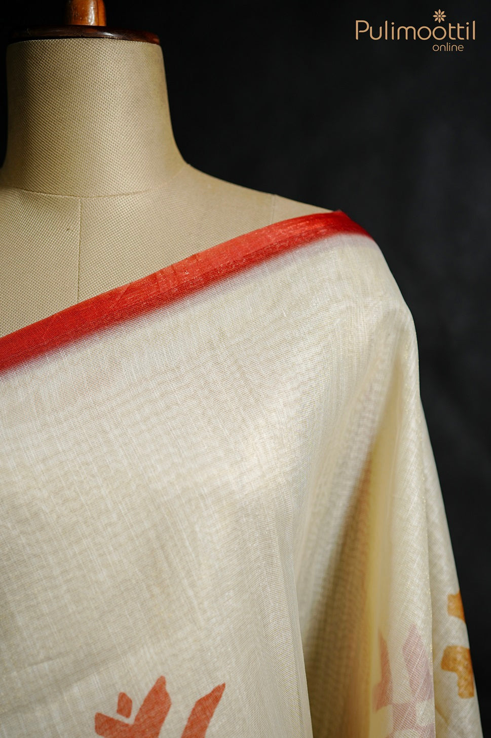 Close-up of cream net cotta saree on mannequin, highlighting red border and shoulder drape on top right side.