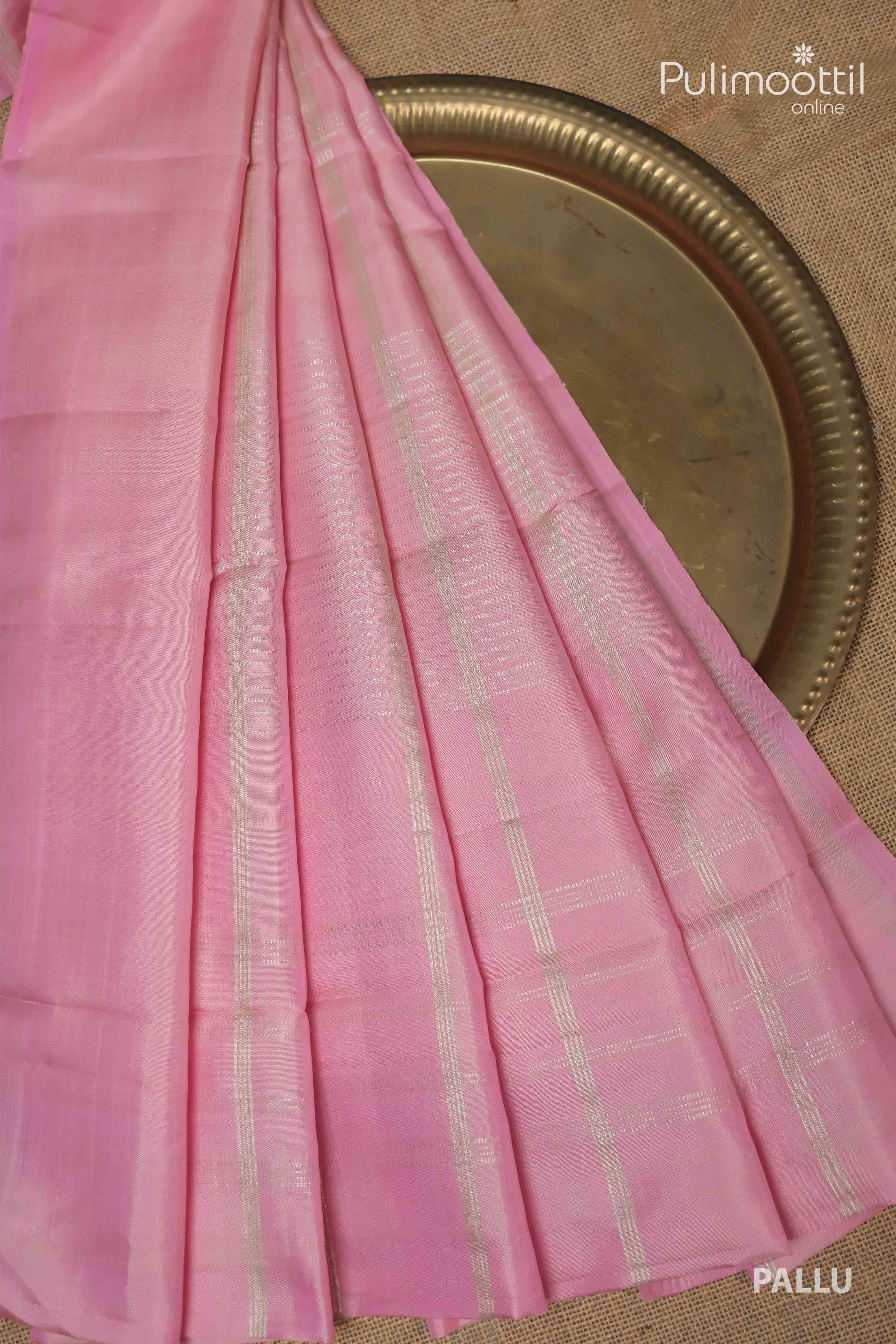 Pallu of cream colour pure Kanchipuram silk saree featuring a soft pink tone with silver checked weaving, neatly displayed on a brass plate.