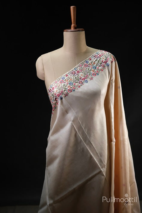 Cream color pure Tussar silk saree with plain body and vibrant multicolour floral thread embroidery on the border, draped on a mannequin.