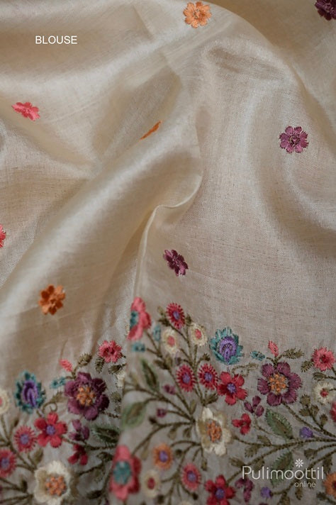 Cream Tussar silk blouse fabric with small multicolour floral buttas and an intricately embroidered floral border in vibrant threadwork.