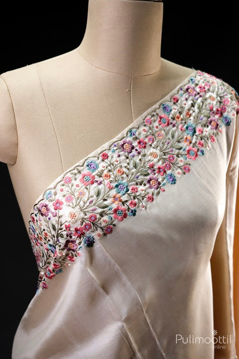 Close-up of cream colour pure Tussar silk saree draped on mannequin, featuring intricate multicolour floral thread embroidery on the pallu border.