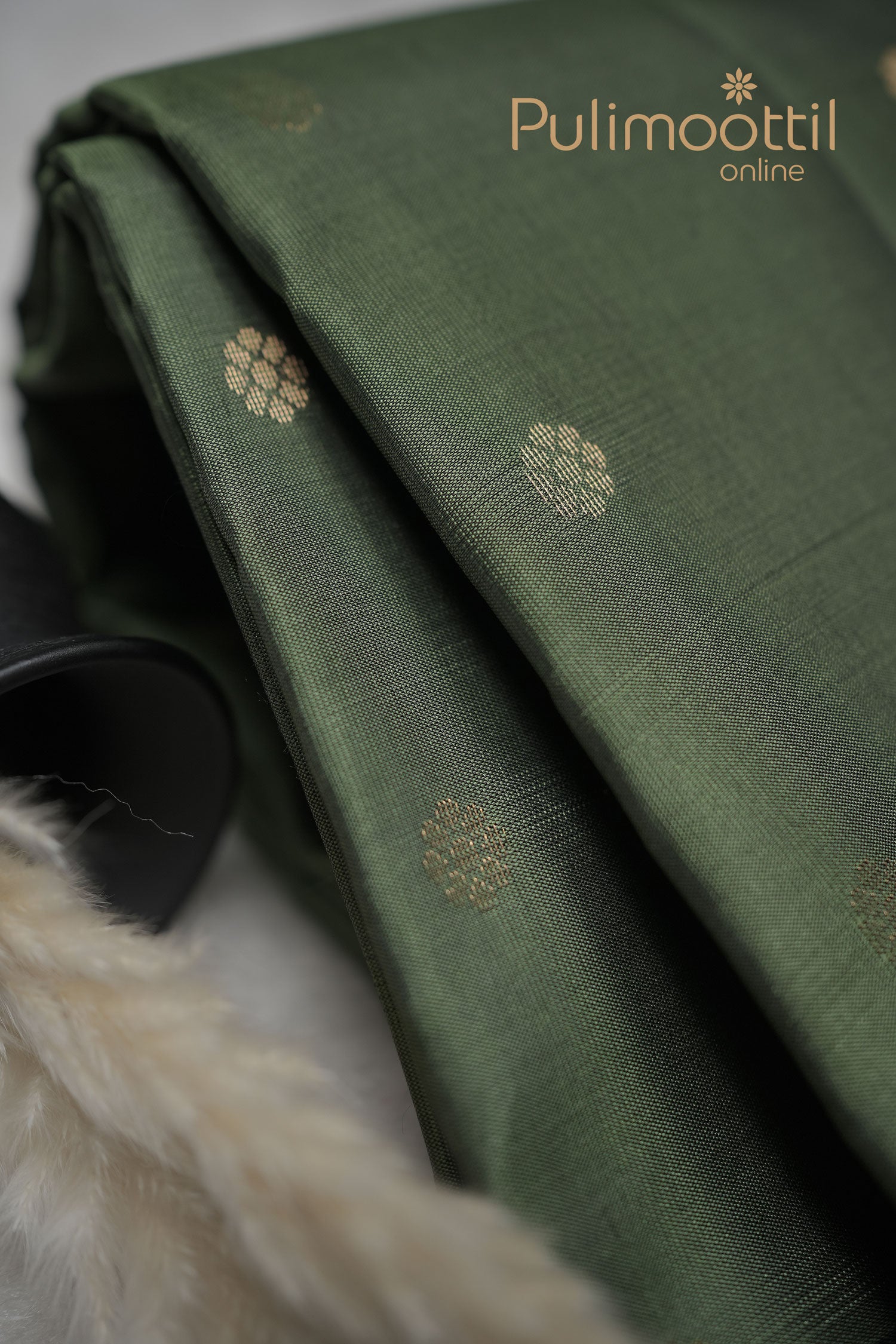 Crocodile green Kanchipuram silk saree with all-over small gold zari buttas and a contrasting woven border, elegantly draped to highlight its rich sheen and traditional weave.