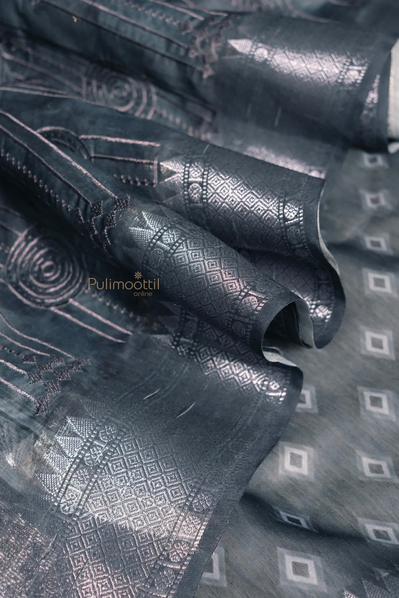 A close-up view of the saree’s pallu and border. The dark spruce blue color is prominent, with a silk texture and gold zari work, giving a rich and elegant look.