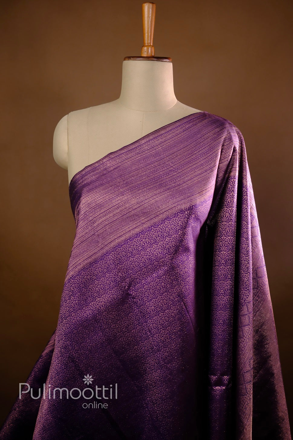 Draped dark purple Kanchipuram silk wedding saree with wide gold zari geometric brocade border.