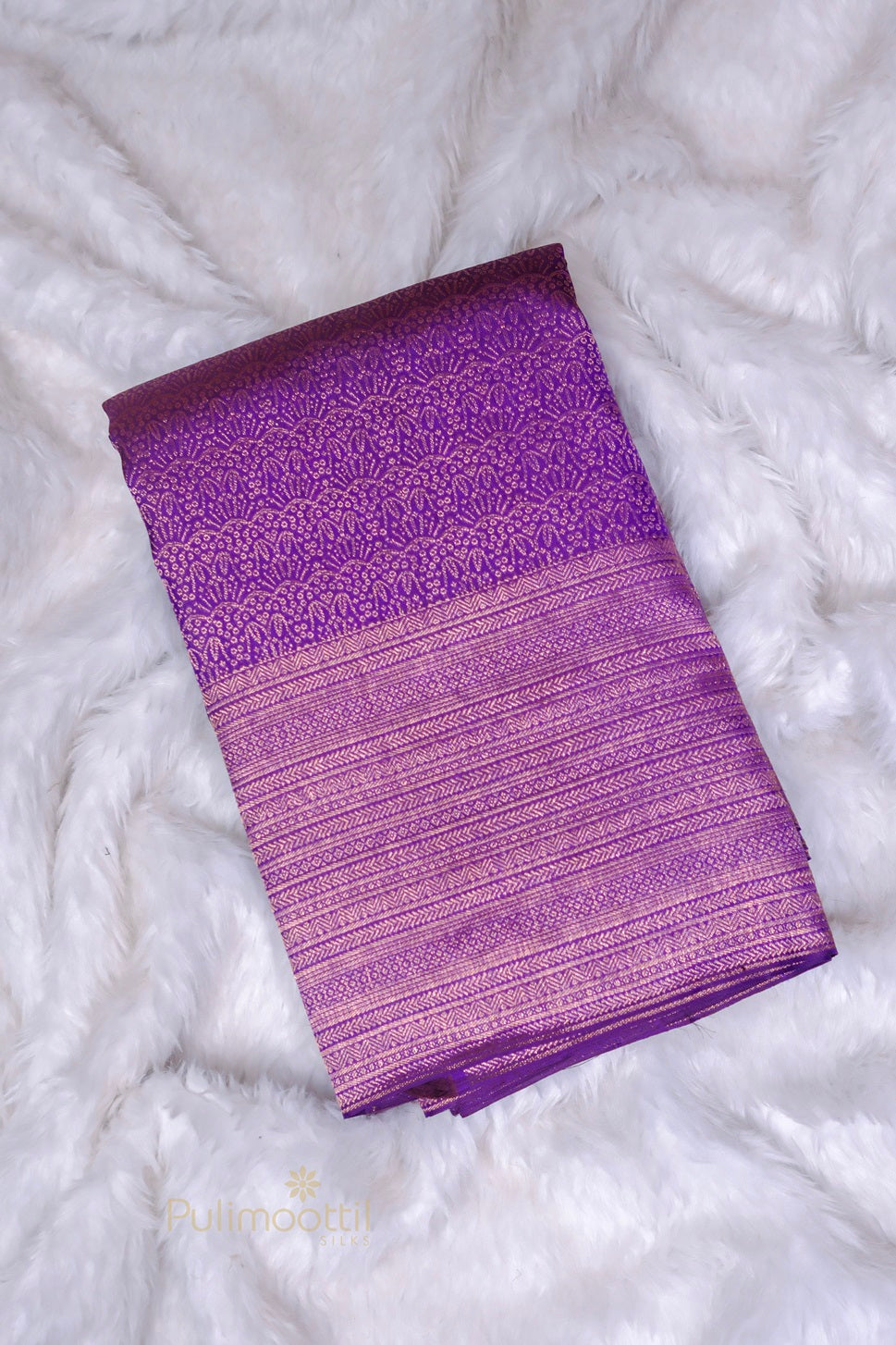 Folded dark purple Kanchipuram silk saree showing rich gold geometric zari brocade pattern.