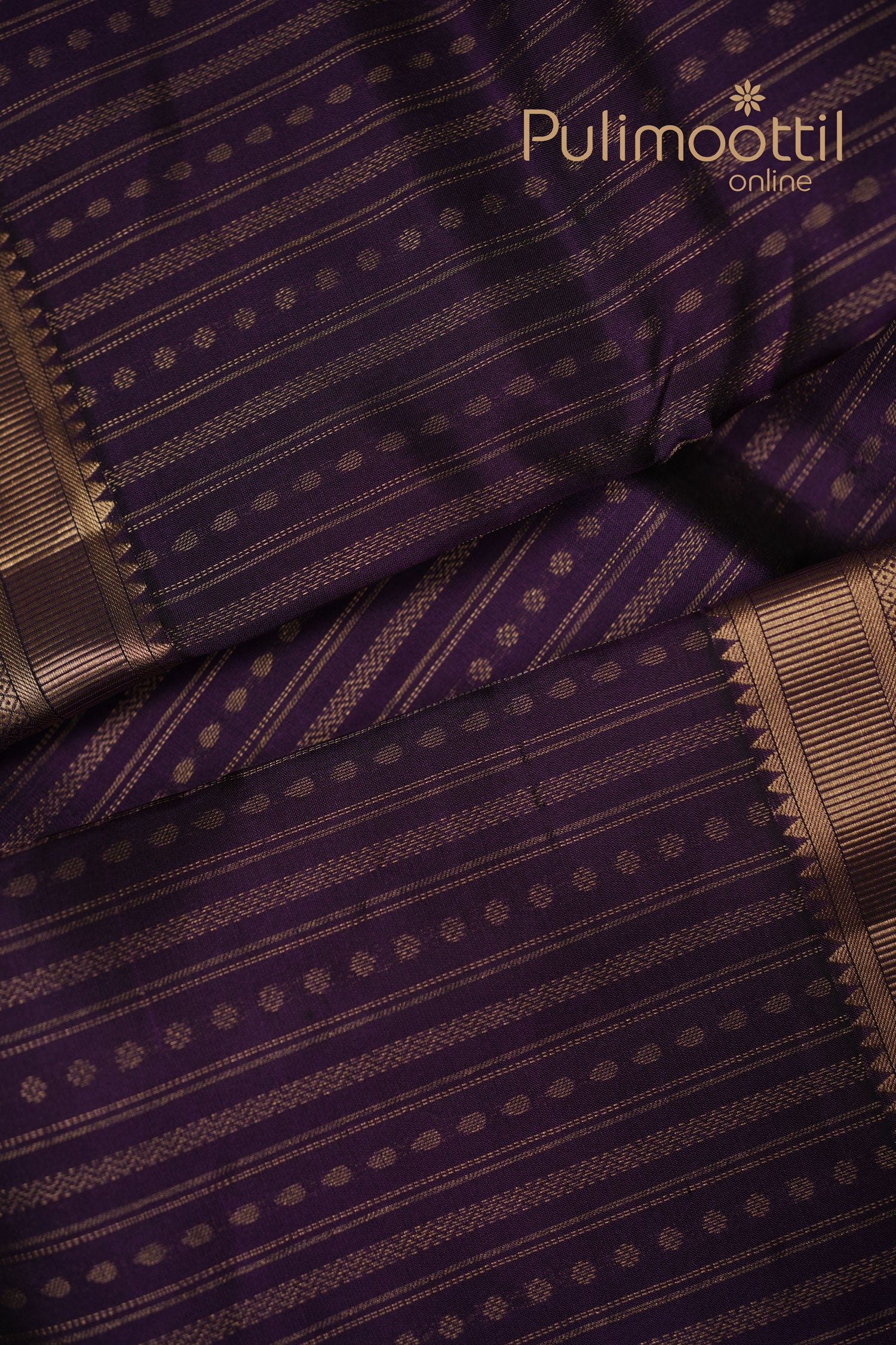 Folded dark purple Kanchipuram silk saree featuring golden zari stripes and small butta motifs, ideal for traditional bridal and festive wear.