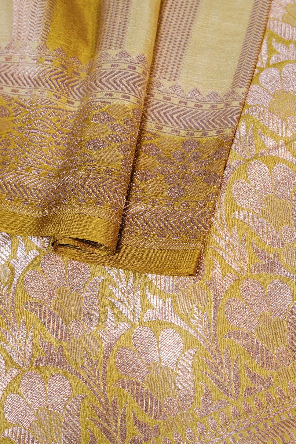 Close‑up of saree’s pallu area with elaborate mauve‑gold floral jacquard design on the golden silk background.