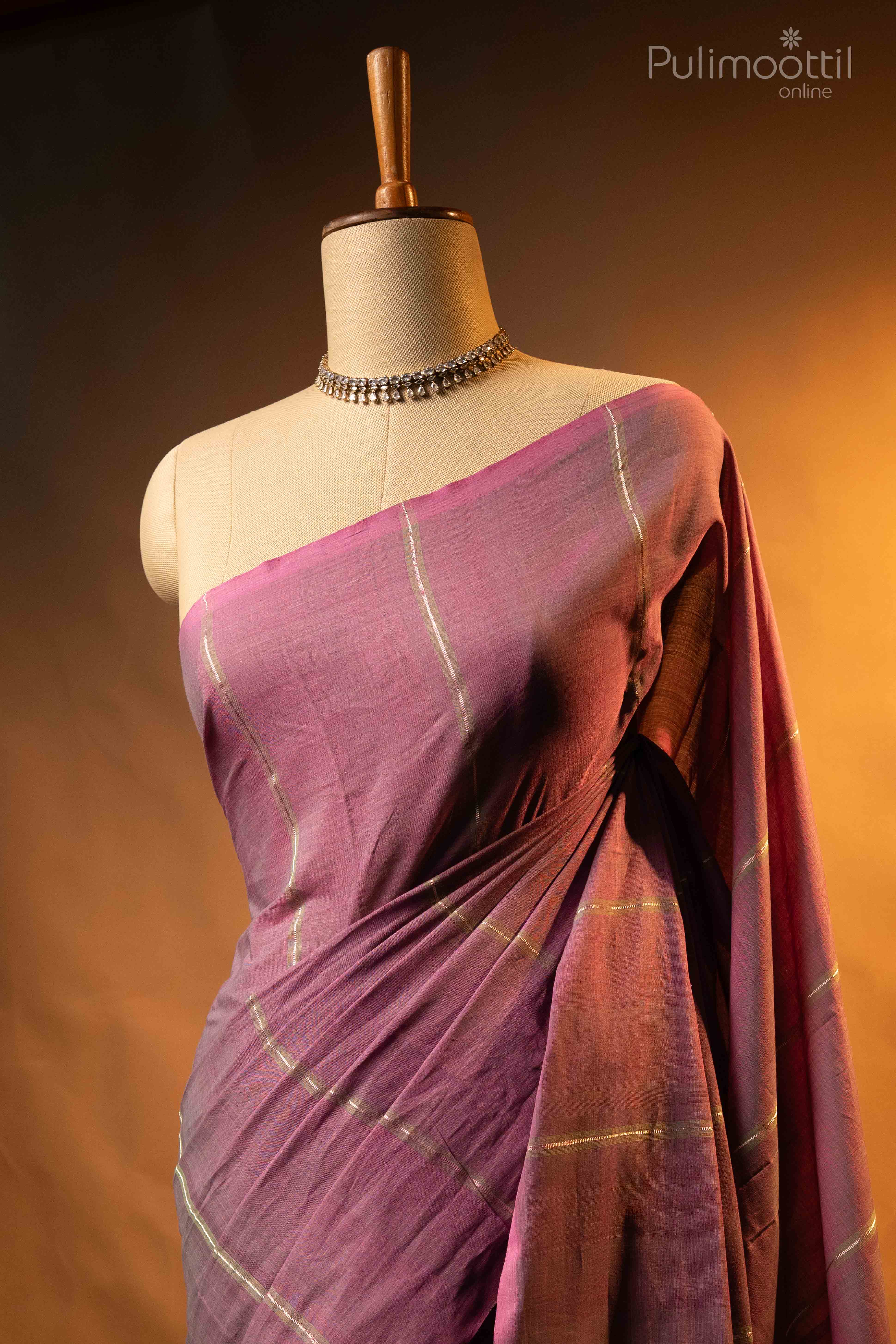 Dusty lavender pure handloom cotton saree draped on mannequin shoulder, showing light green and silver zari stripes on lavender body, no border