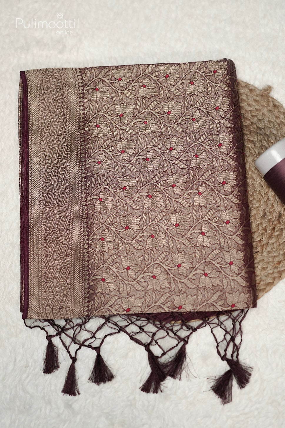 Close-up of Saree Pallu with heavy gold zari weave, deep maroon tassels, and floral body pattern with red accents.