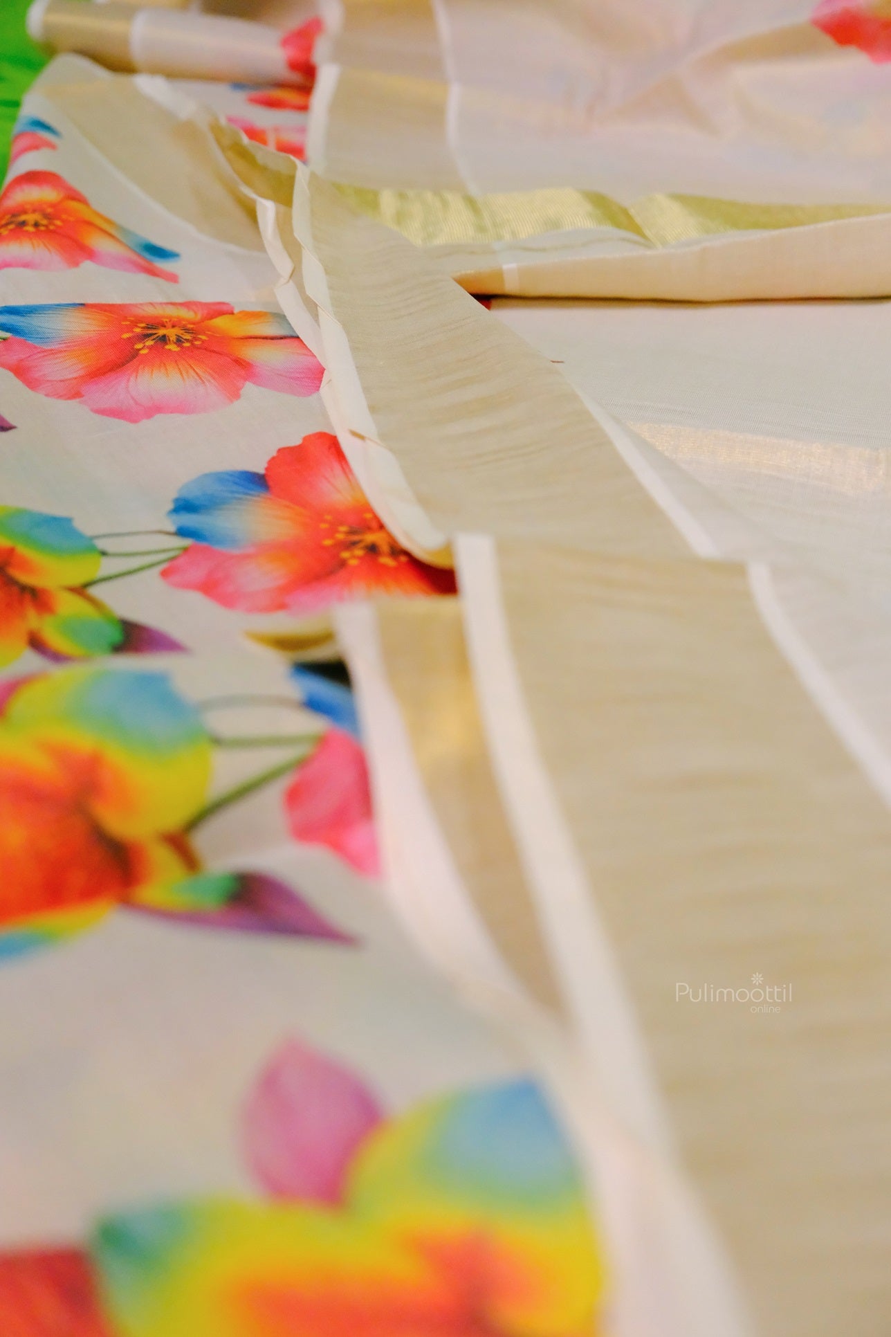 Soft cream Kerala saree adorned with colorful flower designs and gold border highlights
