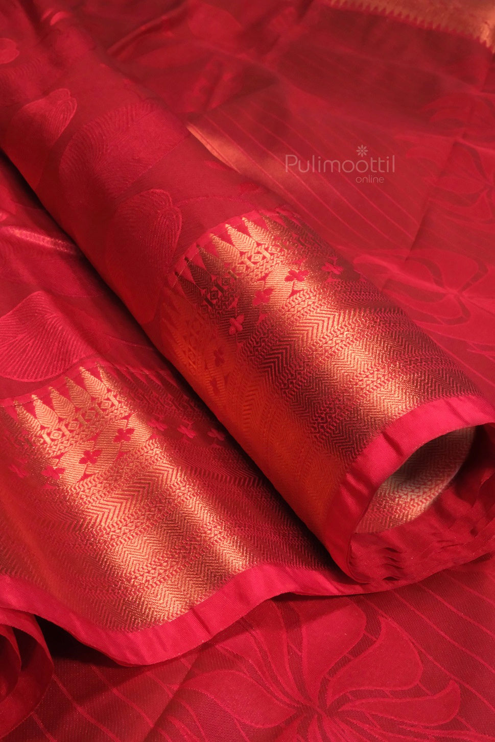 Close-up of the pallu and border detailing on a red Kanchipuram saree, showcasing ornate gold zari temple motifs.