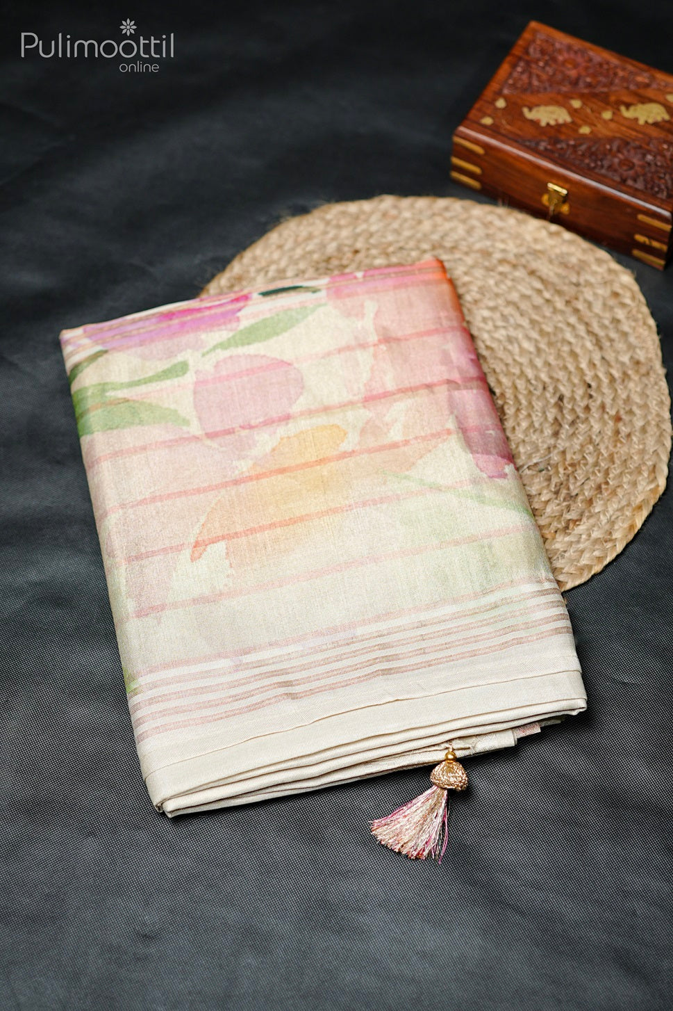 Folded golden tissue fancy saree with pastel floral print and tassel detailing, displayed on flat surface.