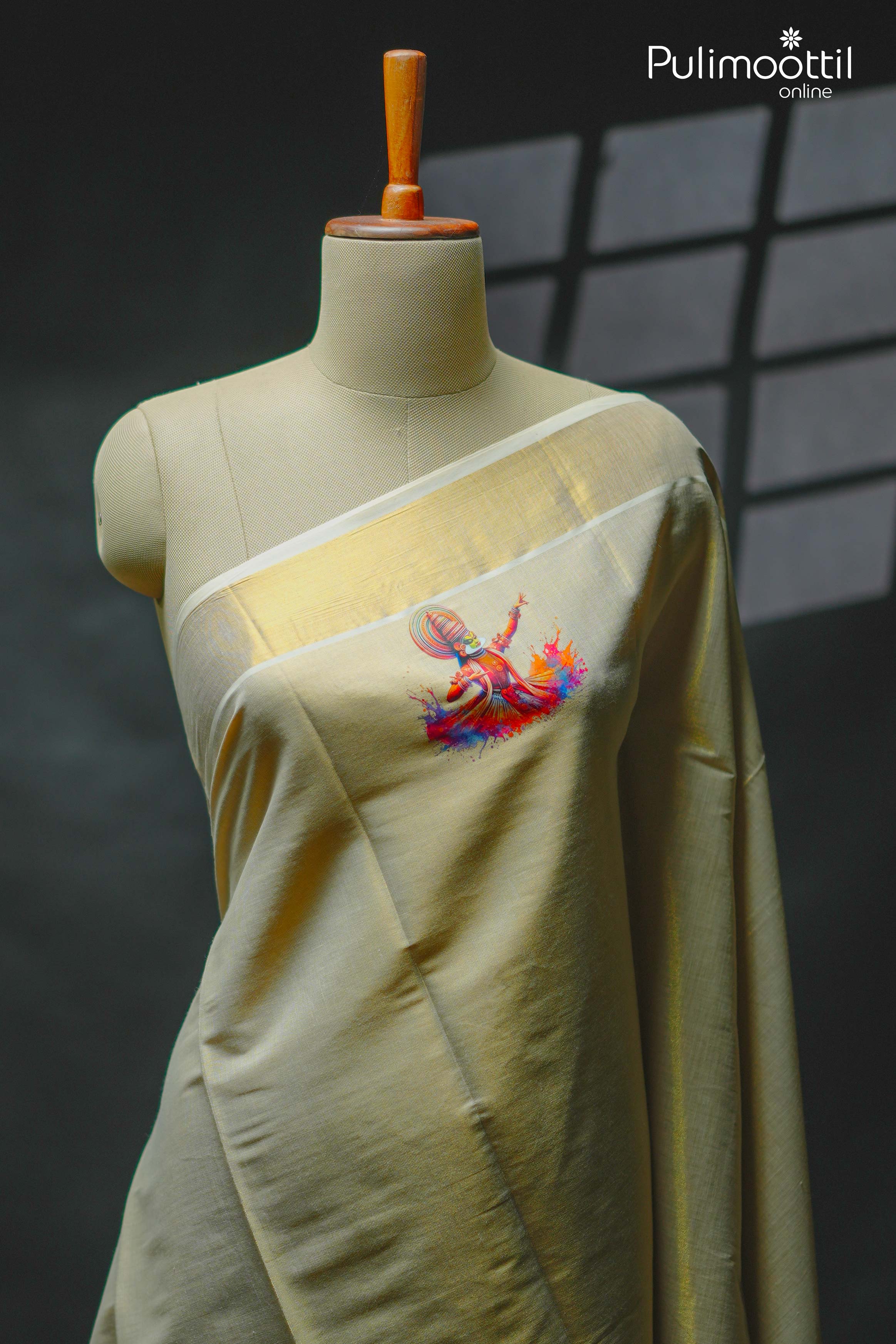 Cream‑gold Kerala tissue saree draped on mannequin featuring bold Kathakali dance digital print on the plain body, golden kasavu tissue border, and maroon Kathakali‑print blouse piece visible at shoulder.