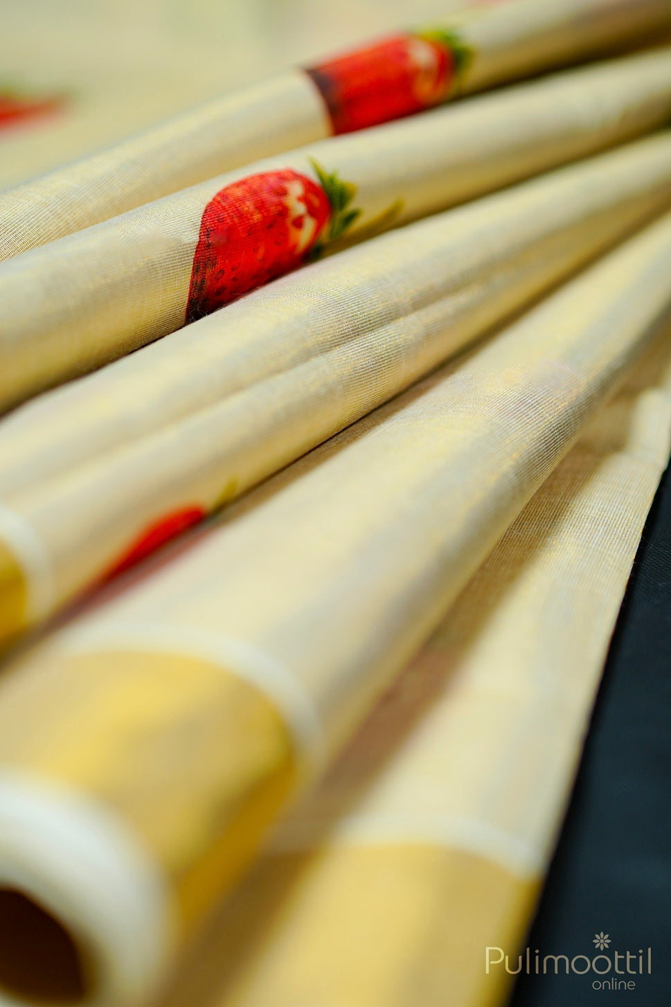 Close-up of saree pleats showing strawberry-print detail near the golden tissue border.