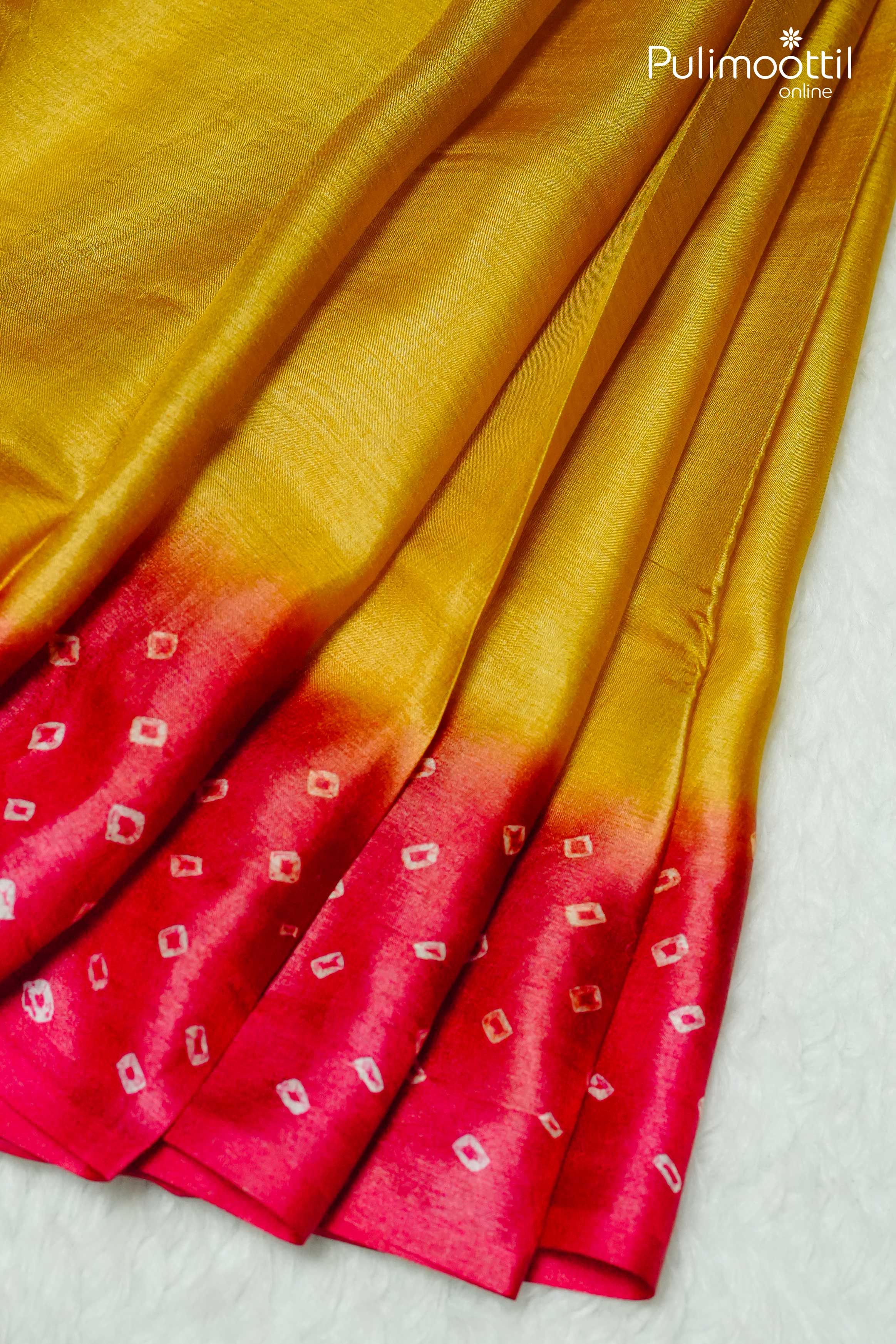 Golden yellow Tussar silk saree pleats with a vibrant red Chungidi design border and white tie-dye motifs, displayed on a soft white background.