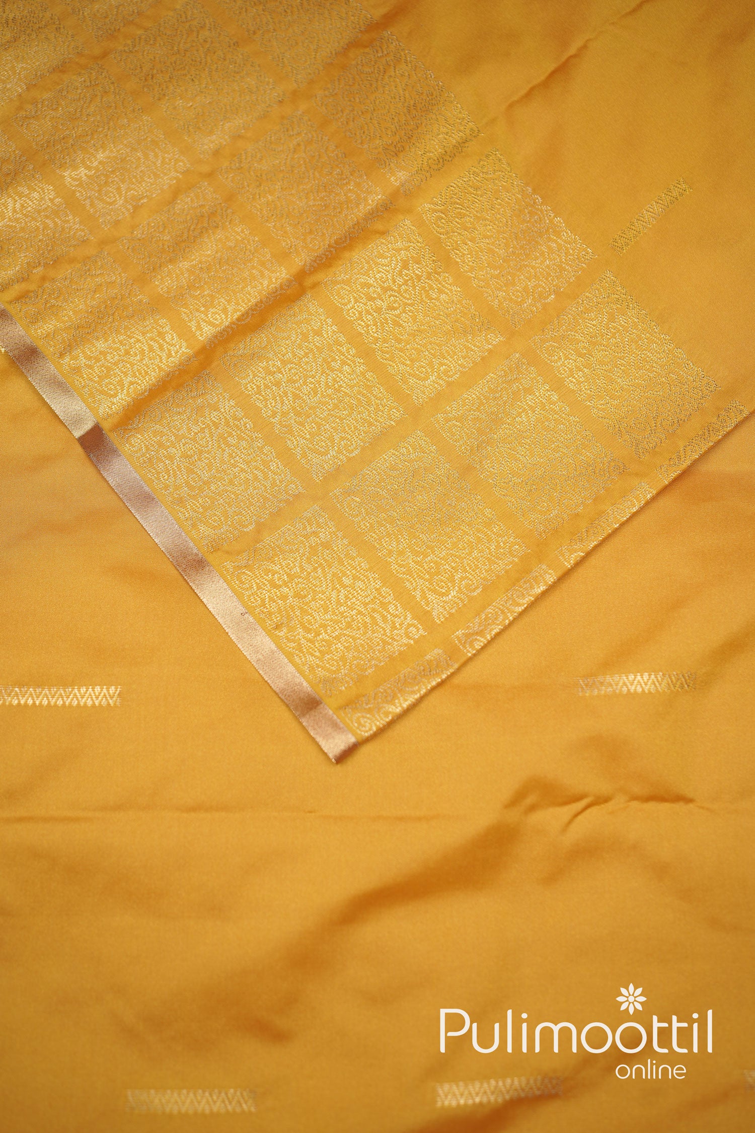 Elegant golden yellow semi-silk saree featuring intricate gold zari motifs and a delicate copper border, perfect for traditional celebrations and festive occasions.