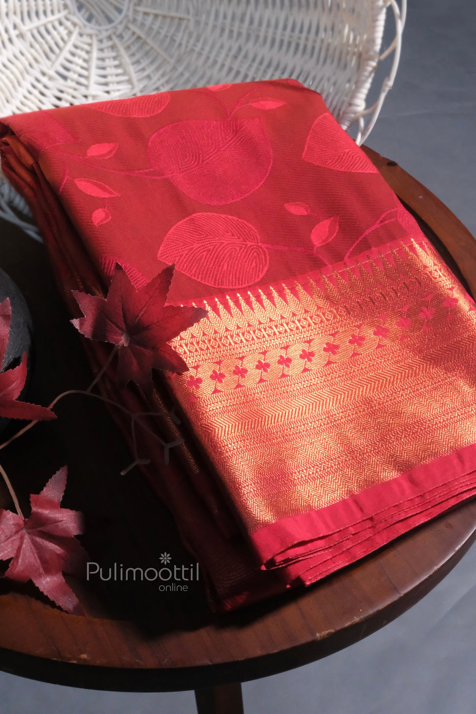 Front view of a model wearing a red Kanchipuram bridal saree with intricate golden zari work, standing gracefully with traditional jewelry.
